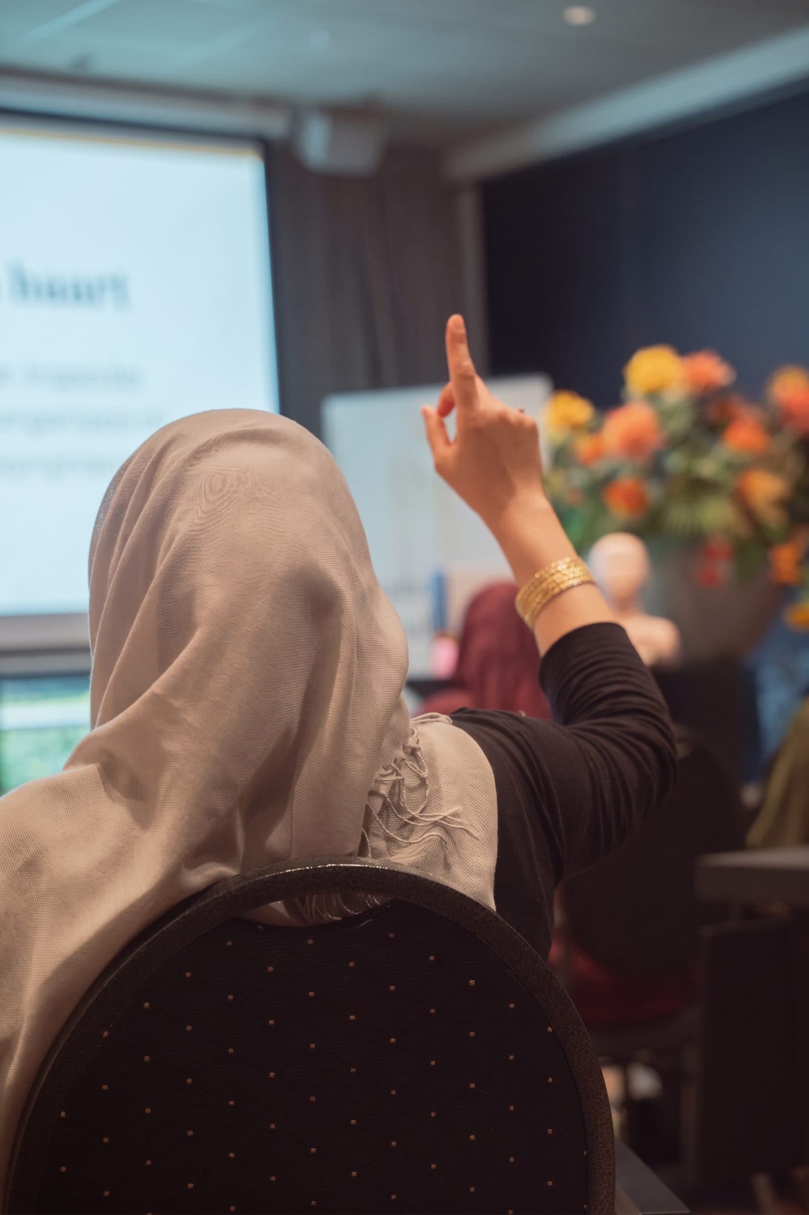 Een studente steekt haar hand op tijdens de les